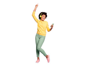 Full length body size photo of curly wavy trendy sweet cute carefree girl dancing and singing while reading song text on her telephone and wearing headphones isolated violet pastel color background