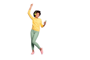 Full length body size photo of curly wavy trendy sweet cute carefree girl dancing and singing while reading song text on her telephone and wearing headphones isolated violet pastel color background