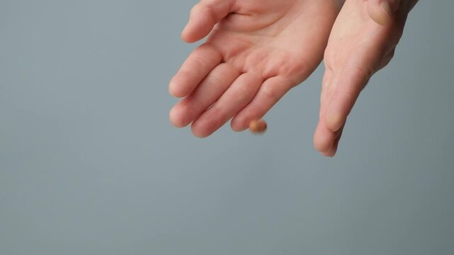 Hands pour brown peanut kernels close-up, slow motion, space for text