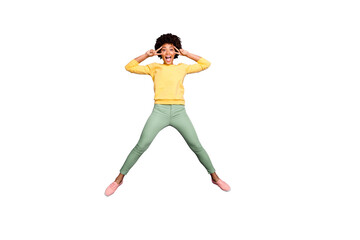 Full body photo of amazed carefree afro american girl jump have fun on autumn spring holidays make v-signs wear yellow pullover green pants trousers isolated over violet purple color background
