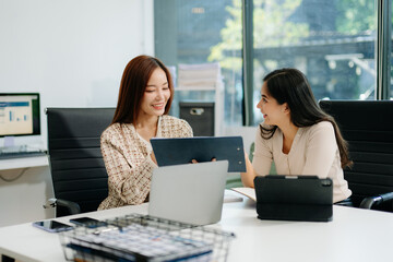 Businesswomen work and discuss their business plans. A woman employee explains and shows her colleague