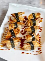 Set of 10 foie gras sushi on white plate.