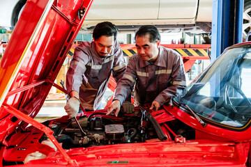 Two skilled auto mechanics examining a red car engine inside a professional garage workshop, demonstrating teamwork, precision diagnostics, and expert vehicle repair service in a business setting.