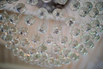 Close-up view of faceted crystal beads on a chandelier, capturing light reflections and details in...