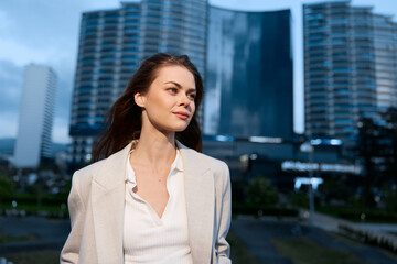 confident woman in beige blazer with city buildings background smiling outdoors modern lifestyle...