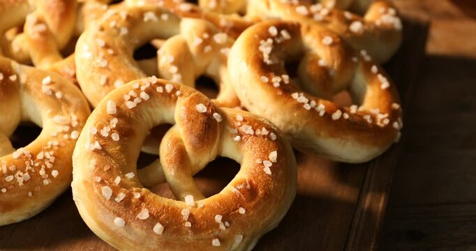 Tasty pretzels on wooden table, closeup. Camera moving left