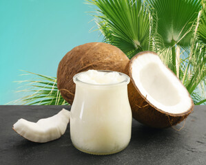 Cooking oil in jar and coconuts on blue table against palm leaves