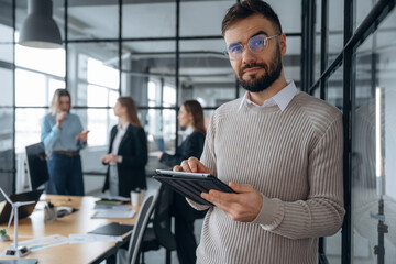 Handsome man is standing. Business people are working in the office