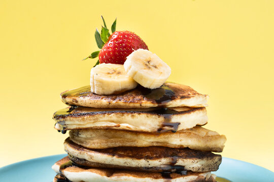 Pancakes with chocolate, strawberry and banana on yellow background