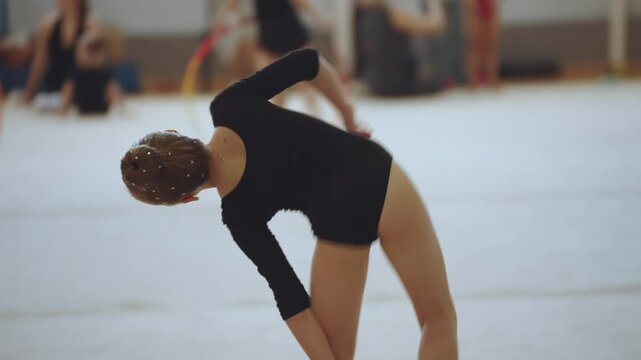 A young rhythmic gymnastics athlete, warming up before performing rhythmic gymnastics