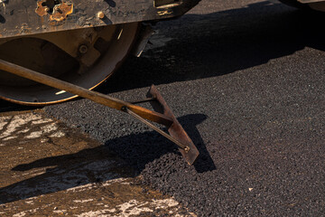 Men at work. A male worker lays asphalt pavement to repair a road.