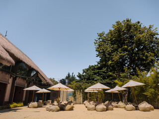 Outdoor seating area on a beach sand with bean bag chairs and umbrellas