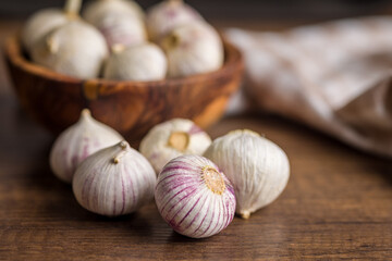 Solo glove garlic bulbs on wooden table.