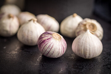 Obraz premium Solo glove garlic bulbs on black table.