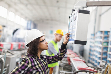 Female worker in factory using control panel for machine