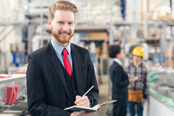 Quality inspector in the factory taking notes and smiling