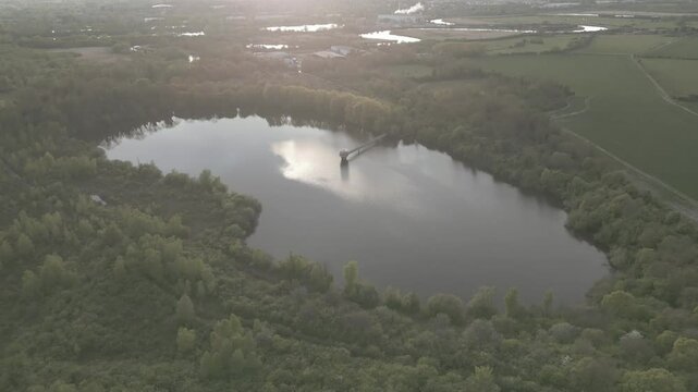 Drone shot of a reservoir at dusk, with a sci looking 1960s or 70s intake tower