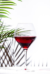 Non-alcoholic, alcohol fries, red wine in glass. White background, palm leaves shadows, hard light