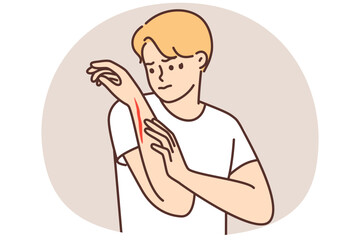 Man examines hand with deep cut or wound received after accident at work