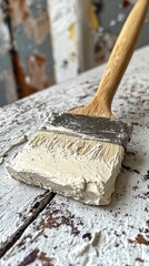 Paint brush applying white paint to a weathered wooden surface close up.