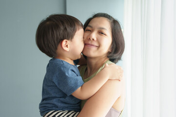 Portrait of Asian Mother and young son hugging and kissing, sharing a tender and affectionate moment