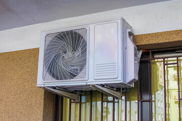 White Air Conditioner Outdoor Unit Mounted on Building Wall with Metal Security Bars in Urban...