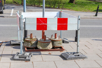 Temporary Road Construction Barrier with Red and White Warning Signs on Urban Sidewalk