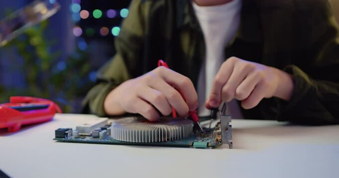 Close Up. Engineer soldering microcircuit. Unknown male hands with a tool repairs a home electronic appliance and screwdriwer on the table at hom.