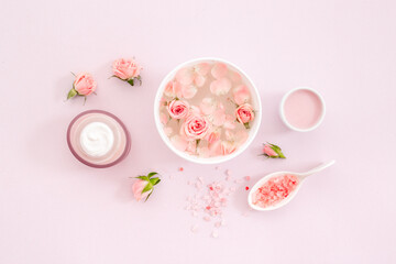Beauty routine concept. Facial roses essence water and face cream with pink flowers and petals, top view