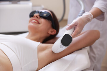 Obraz premium Smiling woman during laser depilation procedure in beauty salon
