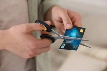 Man cutting his credit card indoors, closeup