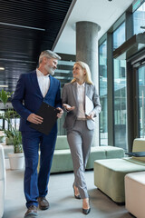 Businessman with his colleague talking while walking in office