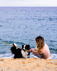 Woman playing with border collie dog on the beach with glucose monitor