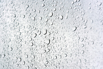 Macro closeup of raindrops scattered across a smooth surface with crystal clear detail showing each droplet's natural shape and texture on calm wet day. Selective focus