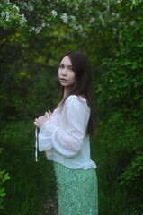 young girl walking in a summer park in a white blouse and skirt