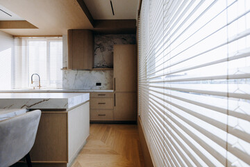 A beautiful kitchen with window blinds and a stunning marble countertop