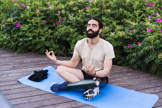 Man with prosthetic leg meditating outdoors on yoga mat in peaceful nature - Powered by Adobe