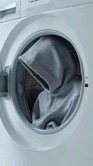 A gray hoodie inside a washing machine, creating a unique and intriguing visual composition that highlights modern laundry routines.