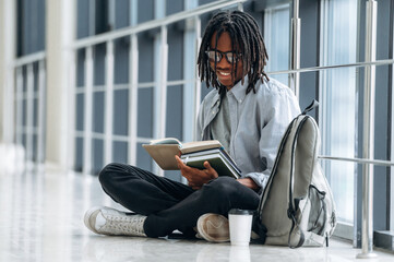 Reading the book. Student with backpack is in the corridor