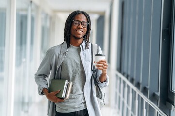 Fresh drink in hand. Student with backpack is in the corridor