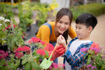 Mother teaching her son how to plant flower. A moment of environmental education and nurturing in a...