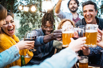 Happy friends celebrating with beer and wine toasting in evening gathering