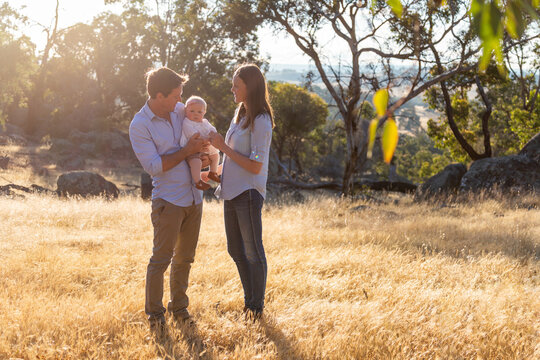 Young parents standing outdoors with their baby
