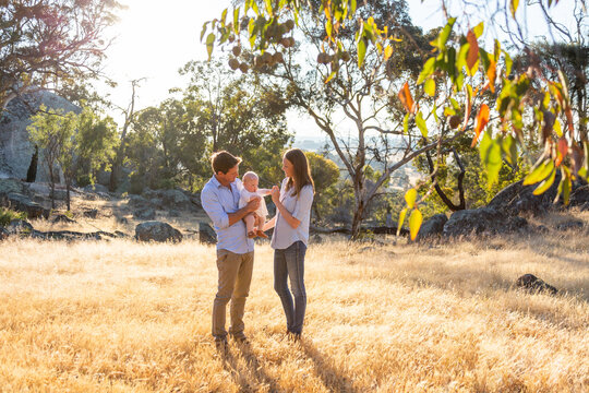 Young parents standing outdoors with their baby