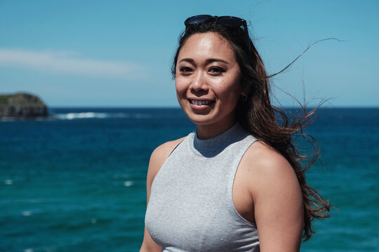 Happy Asian young adult woman with blue ocean background on summer day