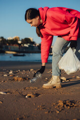 A female ecologist volunteer cleans the beach on the seashore from plastic and other waste....