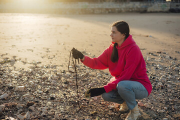 A female ecologist volunteer cleans the beach on the seashore from plastic and other waste....