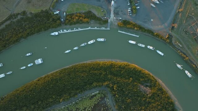 Aerial view of boats moored along a river in Australia. The boats are docked near a marina and surrounded by lush green vegetation. The scene captures a tranquil coastal lifestyle. , CLEVEDON, NZ