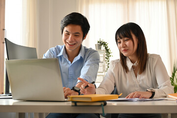 A Young Asian Business Team Collaborating at Laptop in Office