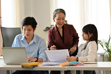 Confident senior executive guiding two young team members, Business teamwork, mentorship, and...